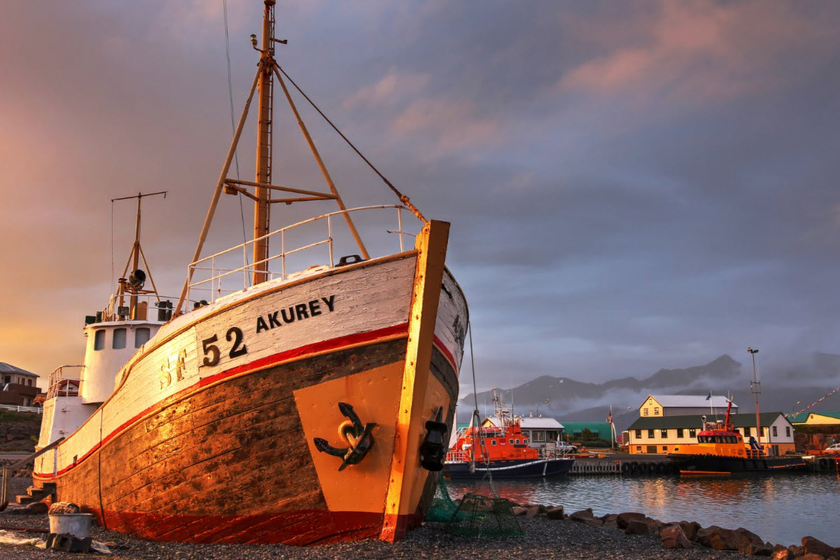 An old shipwreck at the harbor in Höfn during a sunset in Iceland